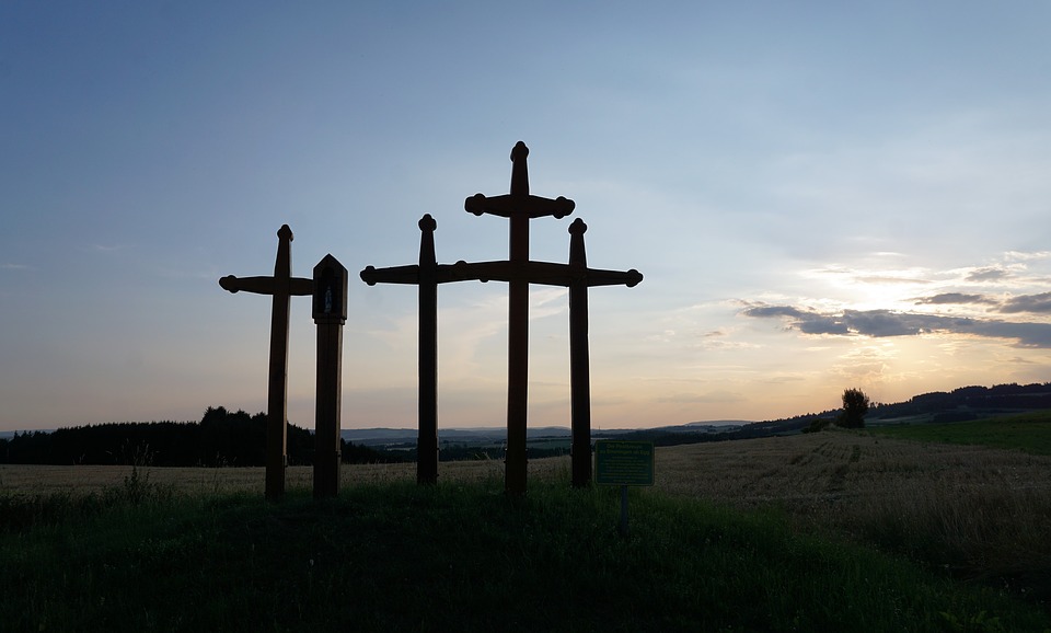 黄昏時の丘の上に十字架が数本立っている
